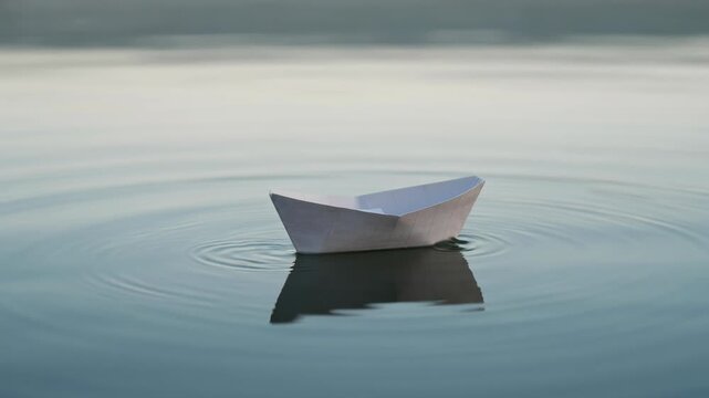 The series of frames depict a small paper boat drifting calmly on a body of water. In the initial frame, the boat is oriented with a slight tilt and creates gentle ripples on the water's surface