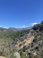 Fototapeta premium Rocky mountain valley with forested slopes and clear sky
