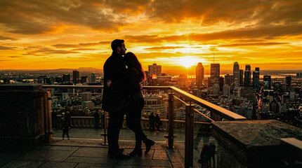 Fototapeta premium Silueta de pareja observando el skyline urbano al atardecer. Concepto de amor, romanticismo y vida en la ciudad.