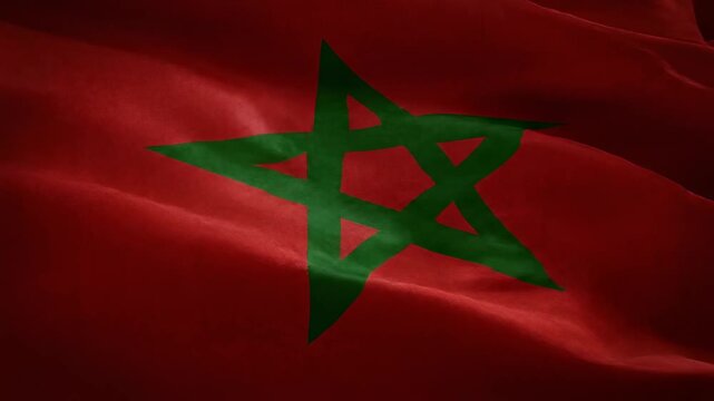Close-up of the national flag of Morocco, featuring a vibrant red background and a green pentagram, gently waving in the wind.