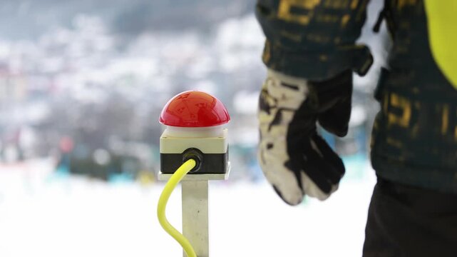 Hand pressing start button to launch ski race at alpine slalom competition