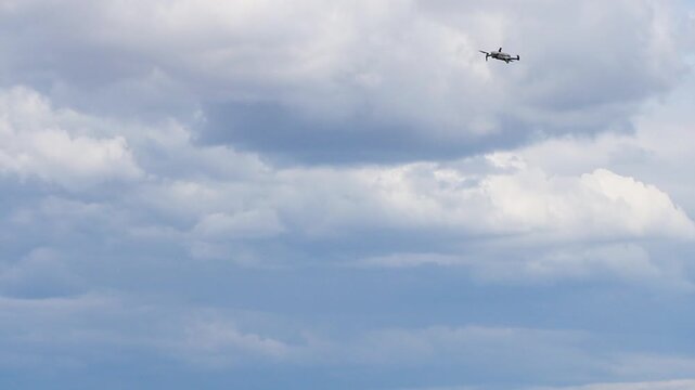 Modern quadcopter drone hovering and flying high in the air against a cloudy white sky background
