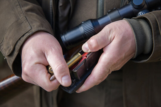 Man with a rifle in his hands.  Close-up of a man loading a carbine with 30-06 cartridges.