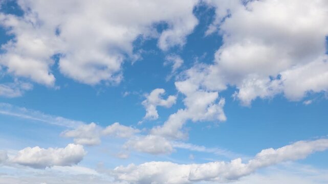 Time lapse of fluffy white clouds moving rapidly across a clear blue sky