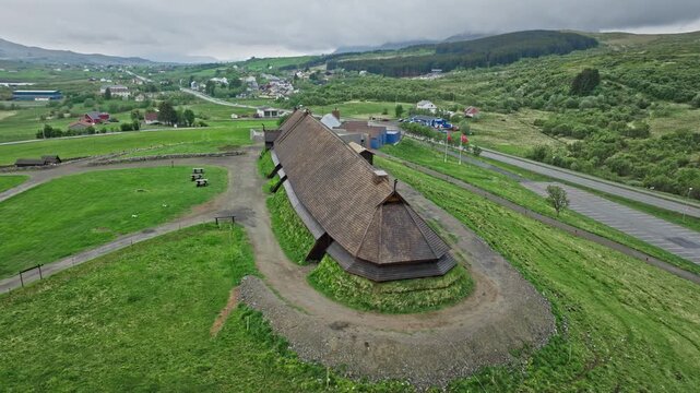 Aerial drone view of the Viking longhouse at Lofotr Viking Museum in Lofoten Islands, Norway. Historic Norse building surrounded by green fields and rural Arctic landscape.