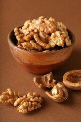 Obraz premium Bowl of tasty walnuts on brown background