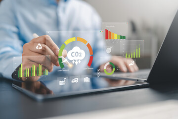 Naklejka premium Businessman use Carbon emission report dashboard for Reduce levels of greenhouse gas, decarbonize industry, energy and transportation. Lower CO2 emission to limit for Carbon neutral and net zero.