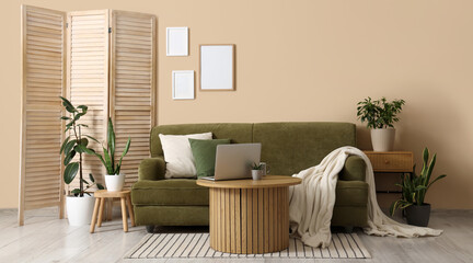 Fototapeta premium Interior of cozy living room with green sofa, folding screen and plants
