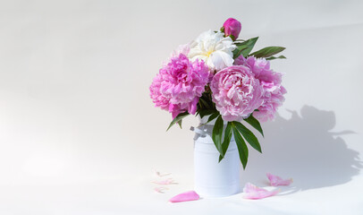 Obraz premium Bouquet of fresh garden pink peonies on a white background. There's a blank space on the left for text and a congratulatory message