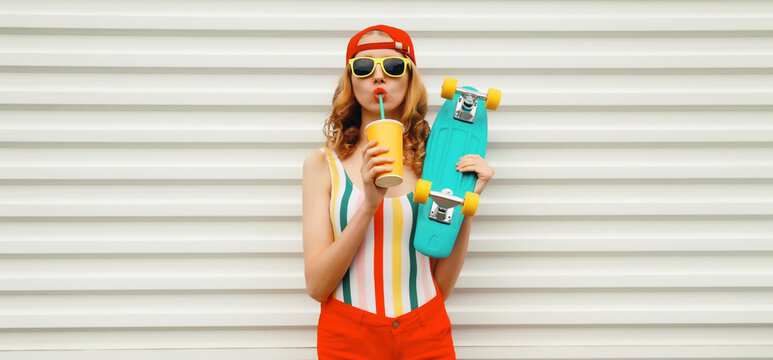 Summer stylish modern young woman with skateboard drinks juice