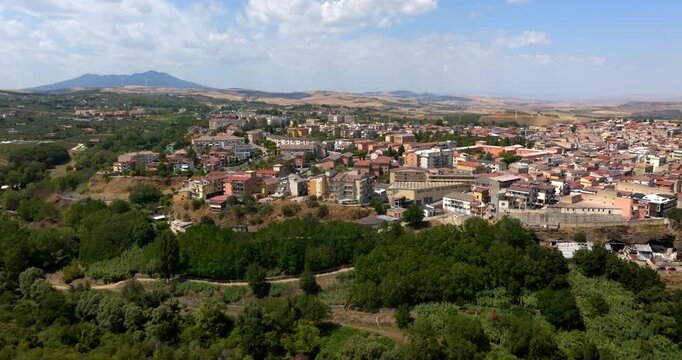 Panoramic aerial view of the city of Venosa, located in the province of Potenza, Basilicata, Italy. Italian town nestled between lush green forests. The urban center features a dense tapestry roofs.