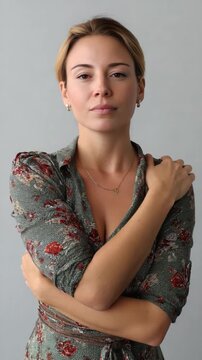 Serene introspection: A woman, her gaze direct and thoughtful, envelops herself in a comforting embrace. Her expression suggests introspection and a moment of quiet reflection. 