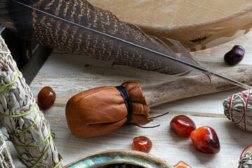 A close up image of the paddle from a mediation drum with sacred feather and white sage smudge sticks. 