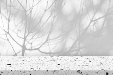 Speckled stucco table, positioned against a plain wall covered in the shadow of tree branches.