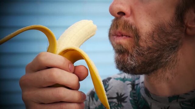 Close-up of a bearded man eating a banana