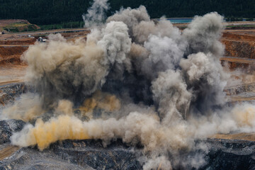 Obraz premium Explosive activity in large open pit gold mine with dust and smoke rising