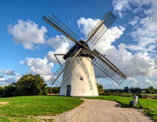 Picturesque windmill stands tall against a bright blue sky with fluffy clouds.