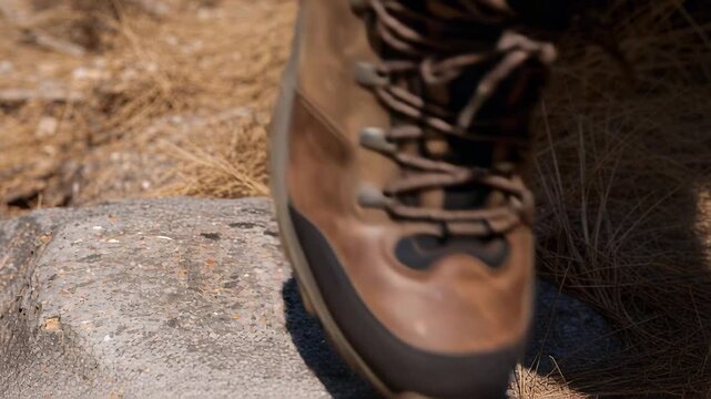 Stepping brown hiking boot planting on flat rock on trail opposite boot entering securing foothold