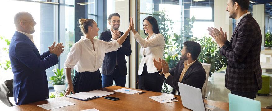 Female confident business leaders give high five on meeting, happy corporate team clapping hands to celebrate agreement. Colleagues applaud teamwork in modern office boardroom with table