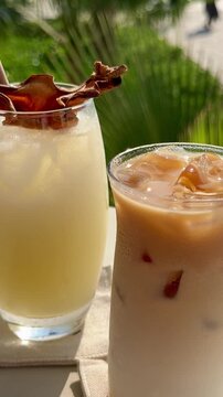Refreshing tropical cocktails and iced latte on a sunny resort terrace in Egypt. Luxury summer vacation lifestyle with cold beverages, garnish, and blurred palm trees background.