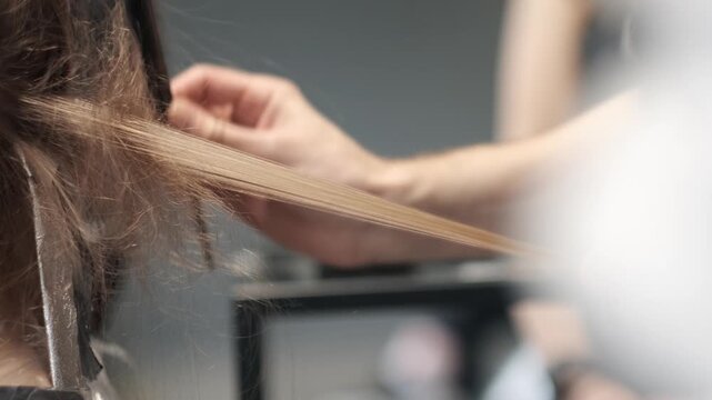 Professional hairstylist using a fine-toothed comb to section long blonde hair during a coloring or treatment process in a modern salon