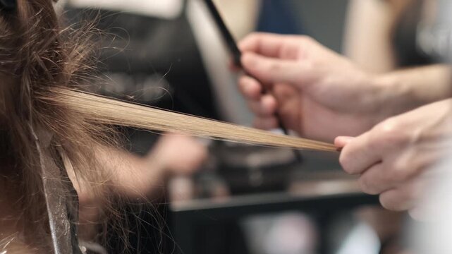 Hairstylist pulling a section of brown hair taut with a black comb during a professional salon coloring treatment