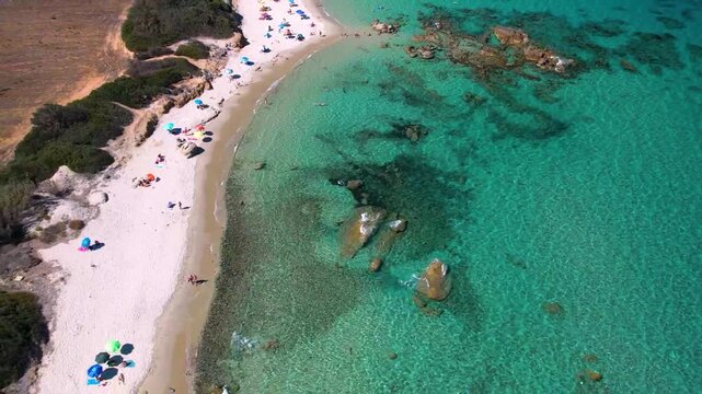 Sardinia Sant Elmo low aerial flight over granite rocks and turquoise sea, Italy Costa Rei white sandy beach, cinematic drone reveal Caribbean water