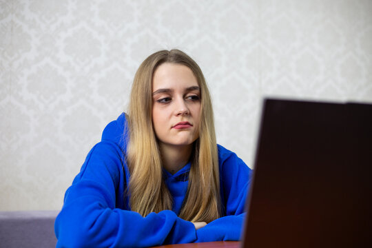Disappointed blonde girl watches boring football match with 0-0 score. She frowns and shrugs shoulders, unhappy with dull game. Negative reaction to live World Cup stream
