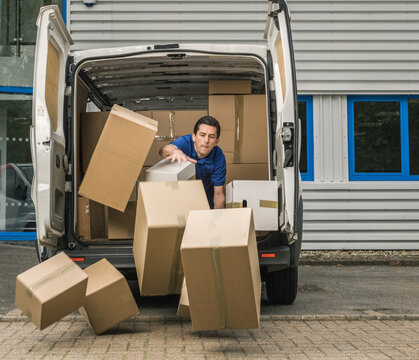 Delivery man trying to stop packages falling from the back of van