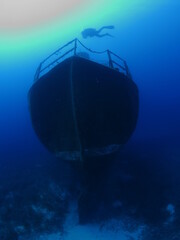 scuba divers exploring and discovering the ship wreck underwater deep sea bottom