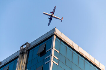 Airplane flying low over business skyscrapers building on blue sky