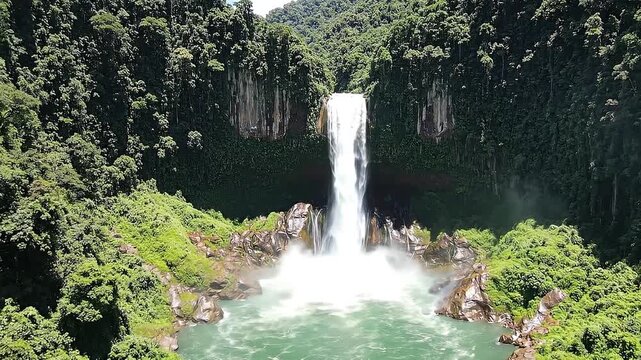 Aerial view of a majestic tropical waterfall hidden in a lush green jungle