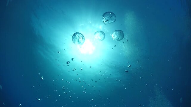 bubbles slow motion underwater coming up to surface with sun beams scenery dark blue backgrounds