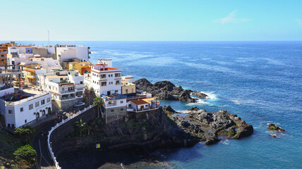 Fototapeta premium cliffside town in Los Gigantes with white homes and red roofs rising above deep blue Atlantic water under clear island light