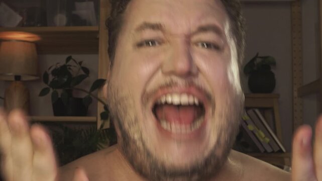 Portrait of overjoyed bearded man standing with excited expression, raising fists, screaming, shouting yeah, celebrating his victory, success.