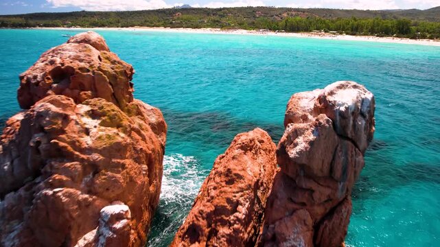 Sardinia Faraglioni di Cea aerial close-up fly-through between red rocks into turquoise sea drone 4k Italy Ogliastra coast cinematic movement travel destination landscape