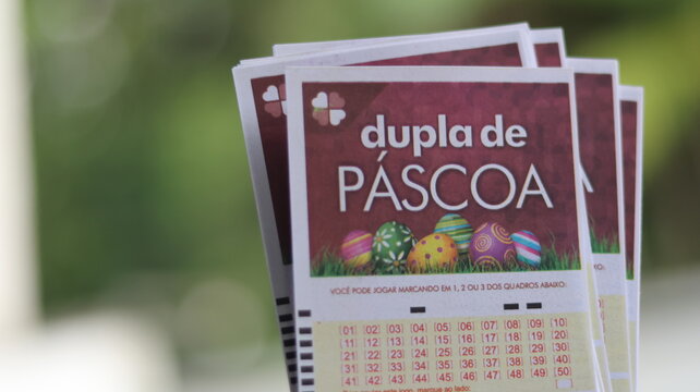 Cartelas da Dupla Sena de P&aacute;scoa seguradas por apostador, representando participa&ccedil;&atilde;o em loteria especial com expectativa de grande pr&ecirc;mio e sorteio tem&aacute;tico tradicional. S&atilde;o Paulo em 12 de mar&ccedil;o de 26