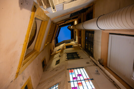 Lyon, france. December 29, 2023. Historic traboule passage with narrow walls reaching up to a deep blue sky, revealing traditional architecture and heritage