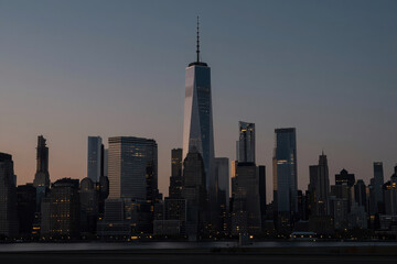 Iconic New York City Skyline at Dusk Featuring One World Trade Center Skyscraper with Illuminated Windows and Urban Architecture Against Fading Sky