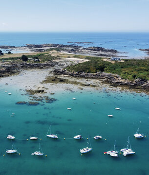 Aerial view of boats floating on turquoise water near the rocky coast, Manche, Normandy, France.