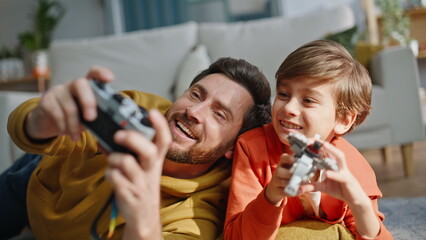 Smiling father taking picture cute little son playing lego lying floor closeup. © stockbusters
