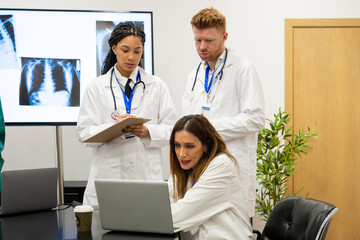 Obraz premium Doctors reviewing patient data and x rays, working together in a medical meeting