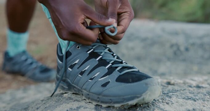Hands, hiking and tying shoelace on rocks for exercise, safety and fitness on summer adventure. Person, legs and hiker with boots, feet and outdoor for wellness, trekking or start on ground in nature
