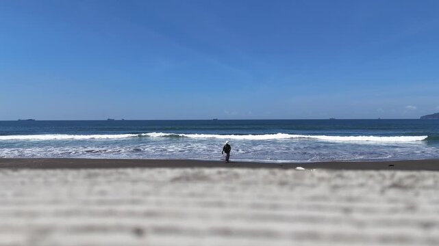 Cilacap, Indonesia - September 12, 2024 Cilacap A construction drone pilot is walking along the beach.