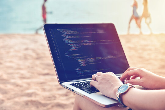 A programmer typing source codes at the beach in a relaxing working environment. Studying, Working, Technology, Freelance Work Concept.
