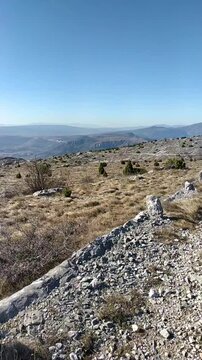 Hiker walking along stone road toward scenic mountains above Mostar. Captures remote Balkan travel experience, solitary trail exploration, and compelling draw highland routes of Bosnia and Herzegovina