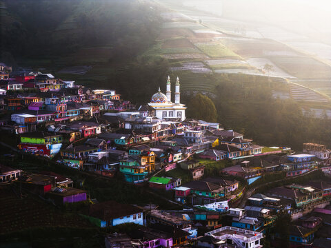Aerial view of a mosque standing tall amidst a vibrant village, nestled against terraced hillsides touched by the warm glow of sunlight, Nepal van Java, Jawa Tengah, Indonesia.