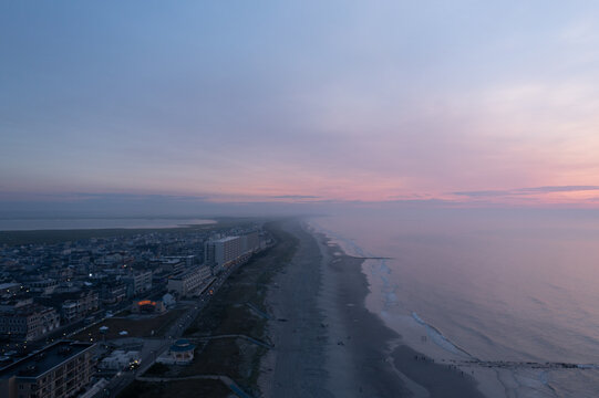Aerial view of the tranquil beachside where the ocean meets the shore under a pastel sky, Sea Isle City, New Jersey, United States.