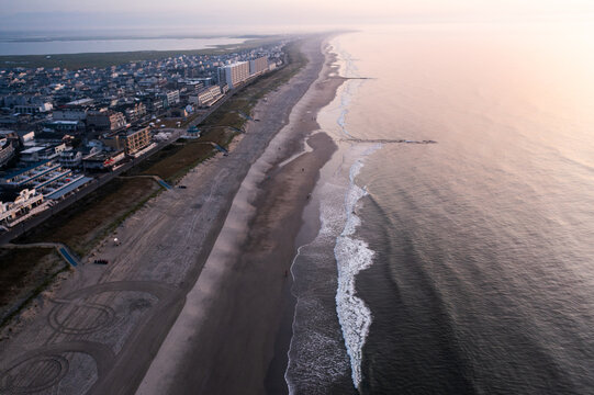 Aerial view of the meeting of the calm, sandy beach with the rhythmic ocean waves under the soft glow of the morning light, Sea Isle City, New Jersey, United States.