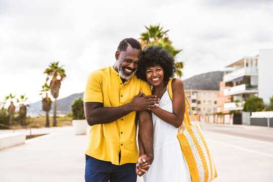 Beautiful mature black couple of lovers dating at the seaside - African senior man and woman bonding outdoors at summertime